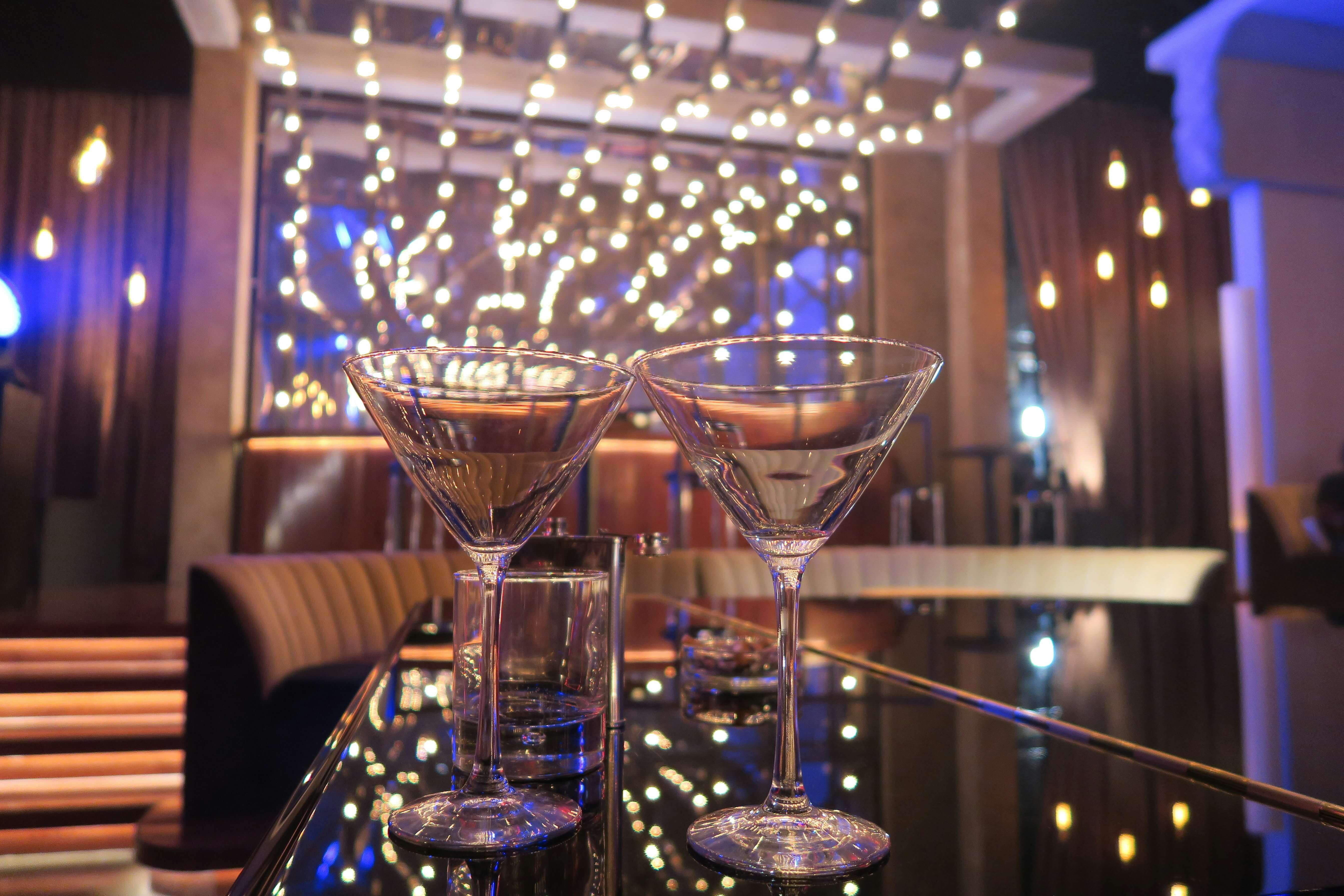 two cocktail glasses on a bar in a sophisticated club bar