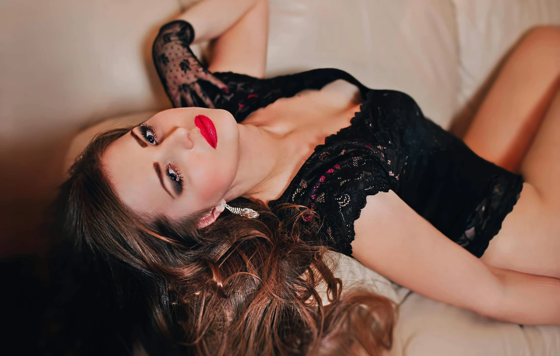 a woman in black lingerie leaning back on a sofa